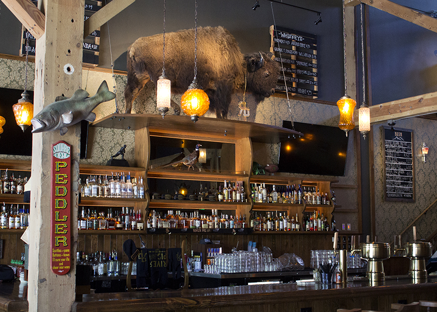 custom bar shelving designed as a throwback to turn-of-the-century saloons, a stuffed bison sits on a shelf above the liquor
